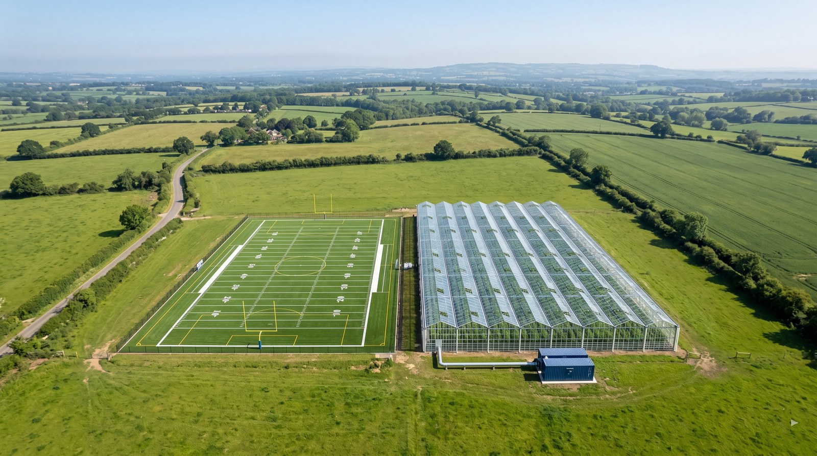 Aerial view of a one megawatt node beside a football field of greenhouse indoor farming, a blue compute container linked to the glasshouse by an insulated heat pipe.